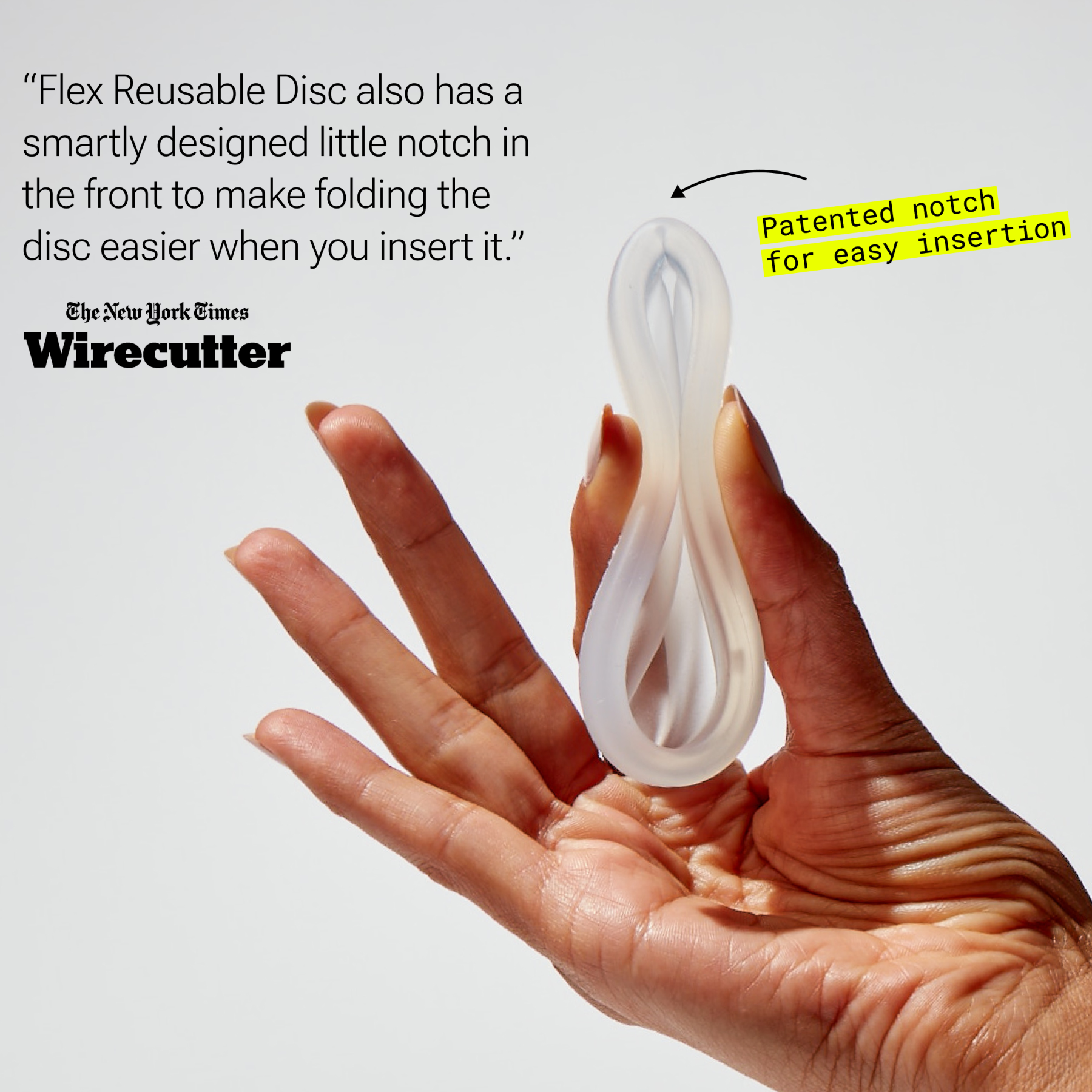 Hand holding folded menstrual disc with visible notch for insertion