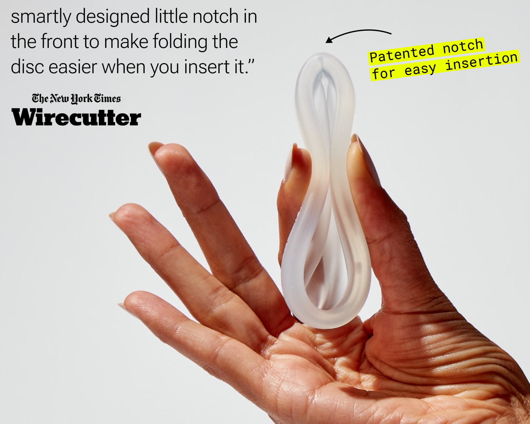 Hand holding folded reusable menstrual disc with visible notch for easier insertion