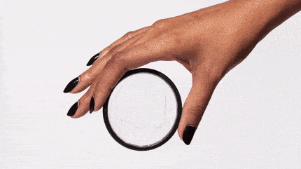 Hand folding a menstrual disc for insertion against a white background