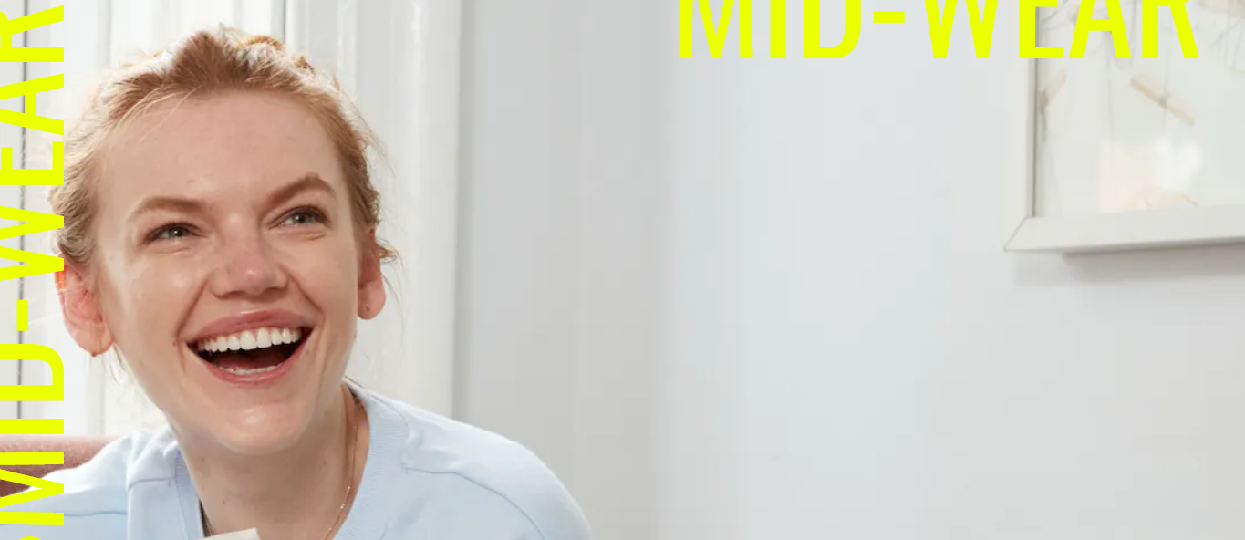 Smiling person against a plain background with text MID-WEAR