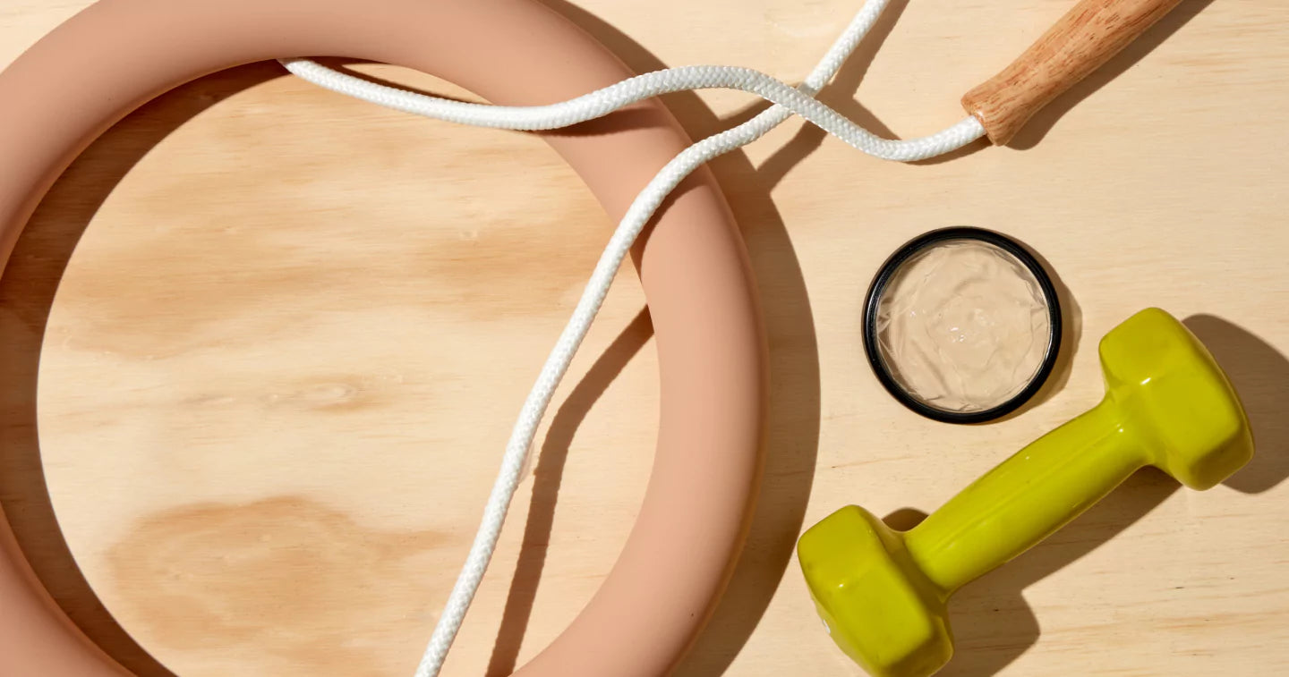 Reusable menstrual disc placed on wooden surface next to workout items including a jump rope and hand weight