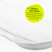 Close-up of menstrual pad with overlay text listing excluded ingredients and material information.
