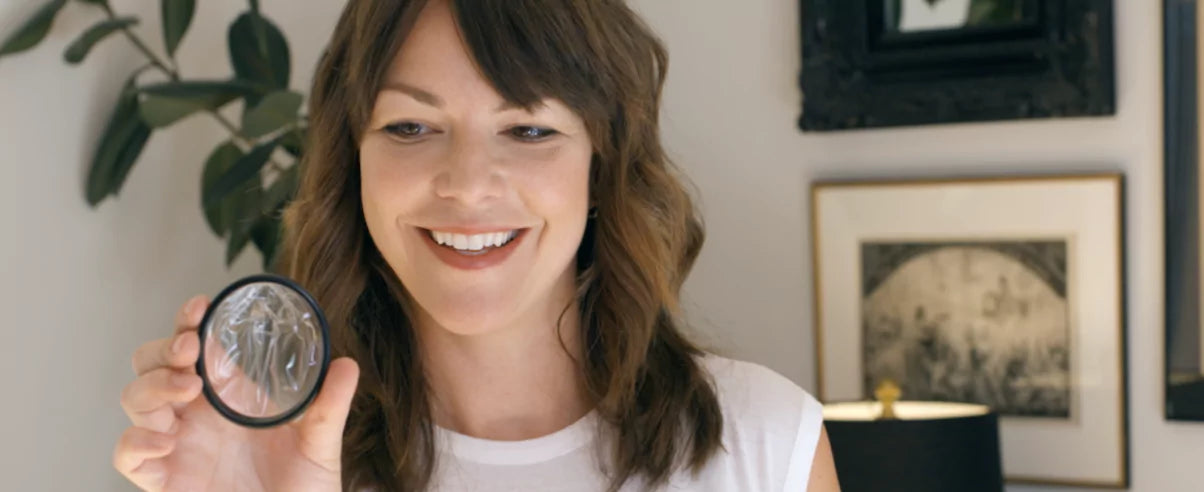 Smiling woman holding a menstrual disc near her face